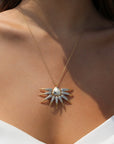 A gold wing phoenix necklace with clear cubic zirconia stones, displayed on a person wearing a white v-neck top.