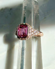 A pink sapphire ring in natural diamonds set in 14k rose gold on a quartz display by Camille Jewelry