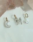 Floating lab created diamond initials in "CMJ" suspended from 14K yellow gold jump rings laying on a quartz stone display , by Camille Jewelry