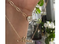 Asscher cut moissanite necklace and the mrs. nameplate necklace in gold being held up on hand by a model | Camille Jewelry
