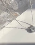 Video of 14K White gold solitaire necklace with halo on a thin chain rotating on a quartz stone | Camille Jewelry