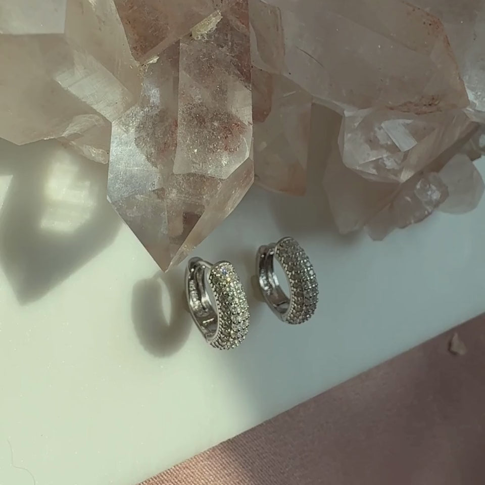 Video of silver domed pave hoop earrings with a quartz display and soft lighting by Camille Jewelry.