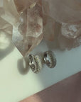 Video of silver domed pave hoop earrings with a quartz display and soft lighting by Camille Jewelry.