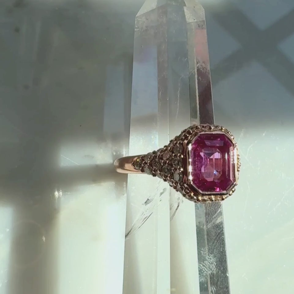 pink sapphire ring in natural diamonds in 14k rose gold on a quartz display by Camille Jewelry.