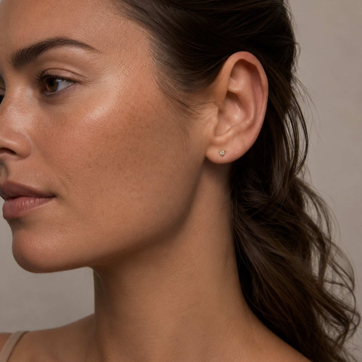 Tiny diamond stud earring in yellow gold worn on model’s ear, Camille Jewelry