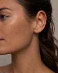 Tiny diamond stud earring in yellow gold worn on model’s ear, Camille Jewelry