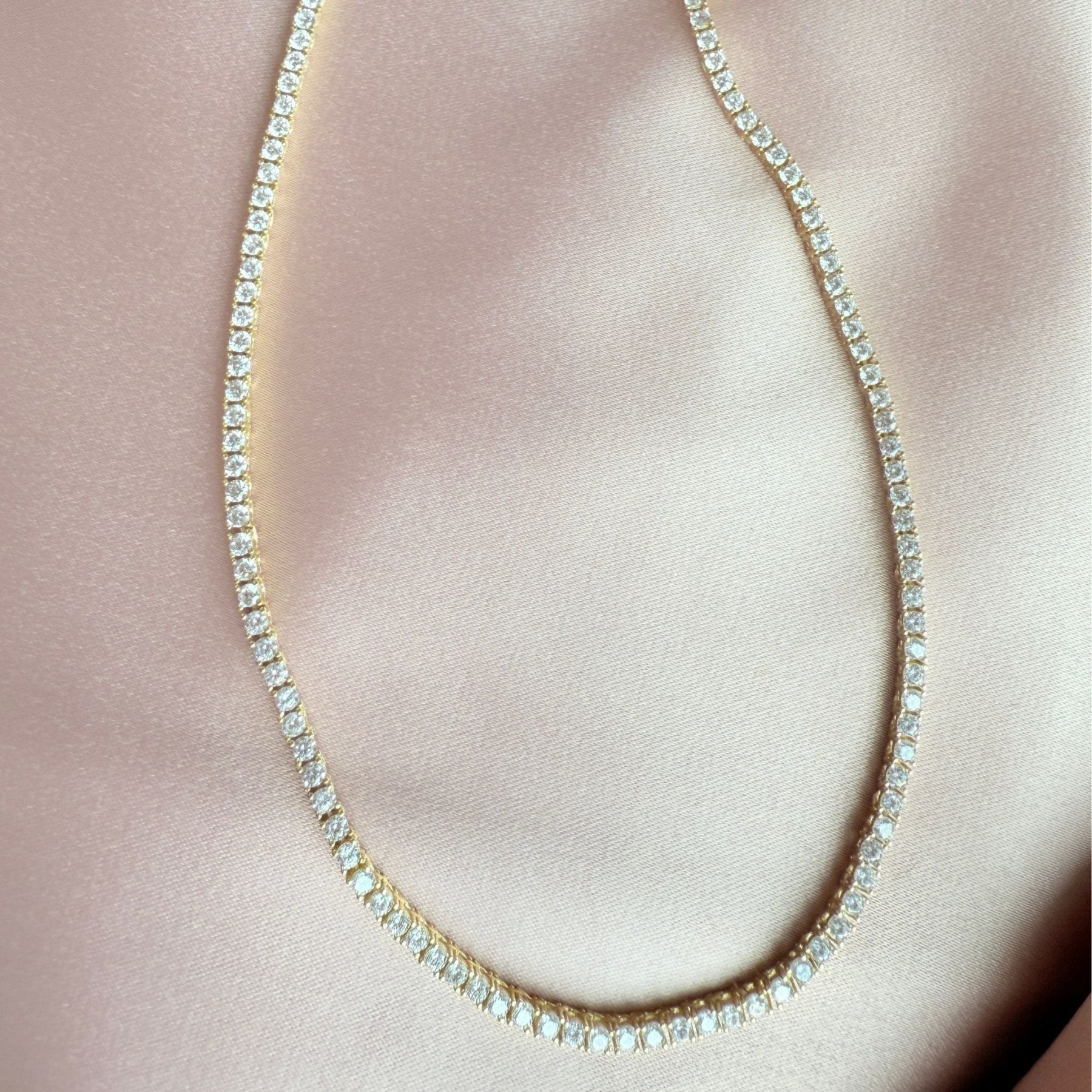 Close up of a tennis necklace with 2.5mm prong set cubic zirconia in gold plated sterling silver by Camille Jewelry
satin cloth