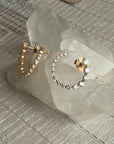 Small diamond hoop earrings in 14K yellow gold 7/8 CTW on a quartz stone display by Camille Jewelry 