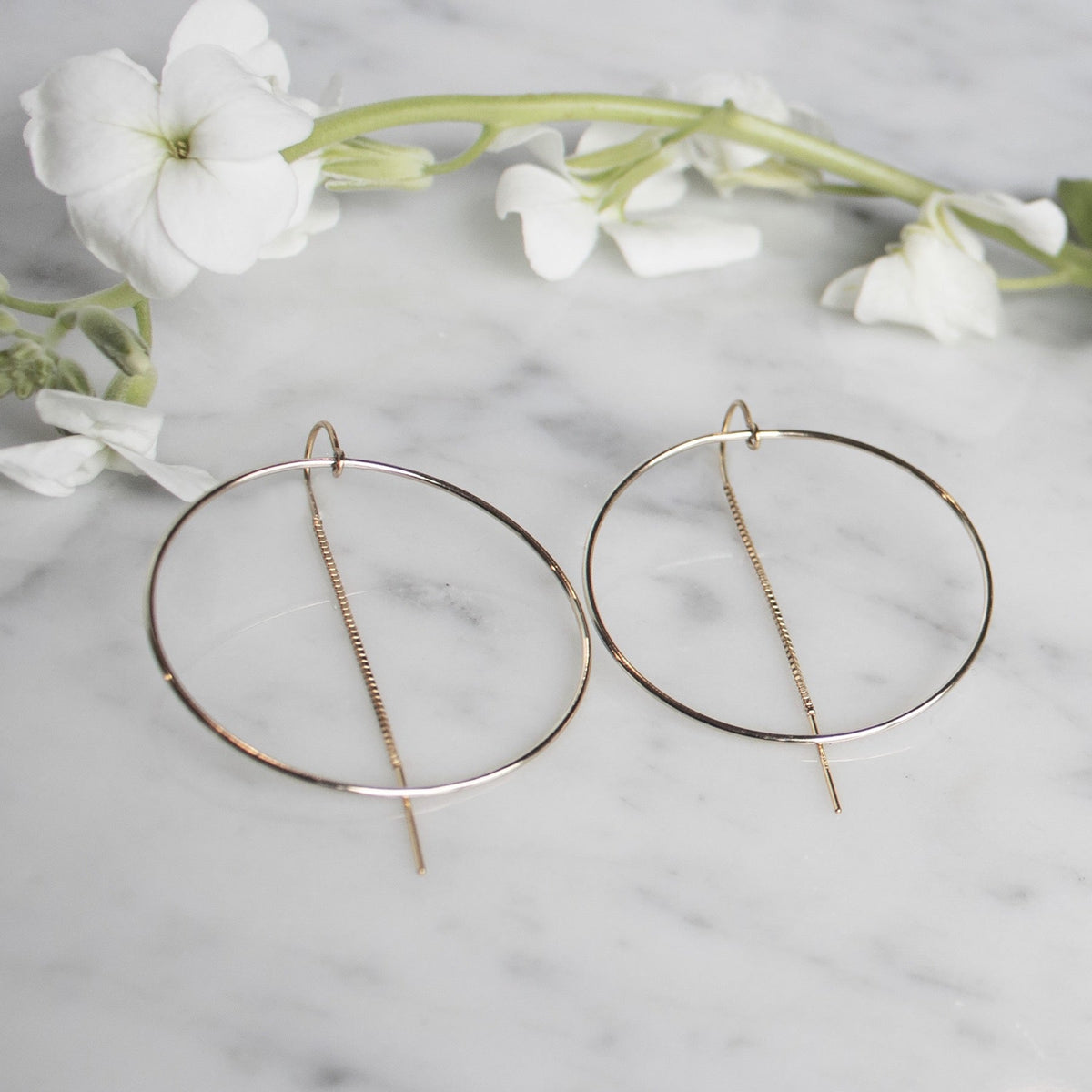 Gold Filled Threader Hoop Earrings on quartz display with white flowers by Camille Jewelry