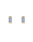 Pair of tiny stud earrings in tanzanite in 14k yellow gold on a white background by Camille Jewelry. 