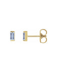Tiny stud earrings in tanzanite gemstone set in 14k yellow gold on white background by Camille Jewelry. 