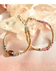 Tourmaline bracelet in 14K gold filled with curved gold tube beads and a pink tourmaline center bead resting on a quartz crystal by Camille Jewelry