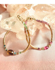 Tourmaline bracelet in 14K gold filled with curved gold tube beads and a pink tourmaline center bead resting on a quartz crystal by Camille Jewelry