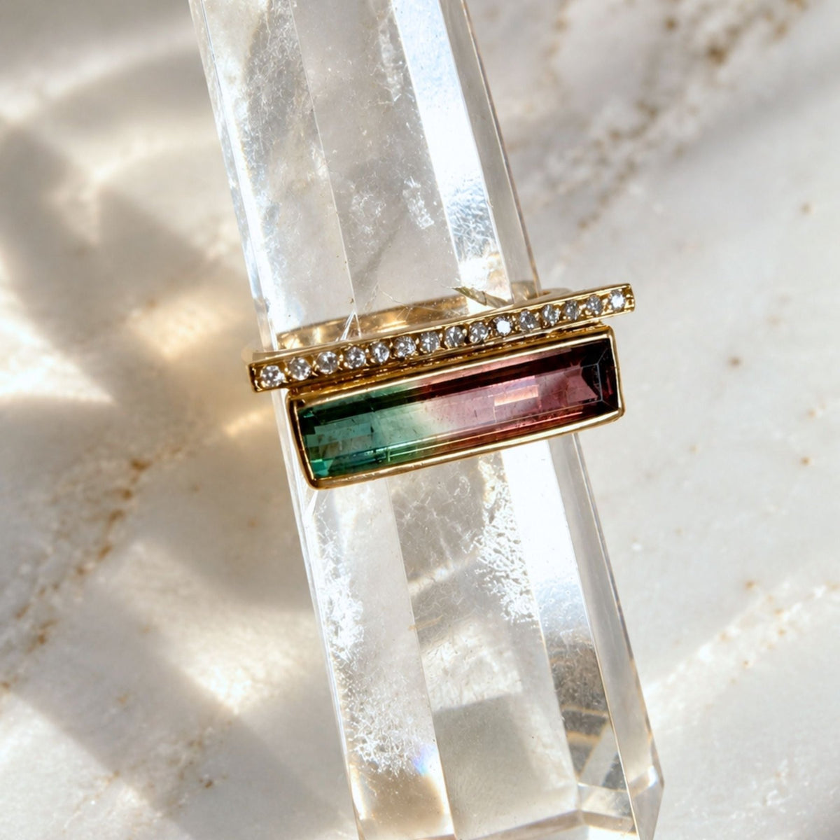 14K gold tourmaline gemstone ring in watermelon tourmaline in a diamond bar design on a quartz display by Camille Jewelry