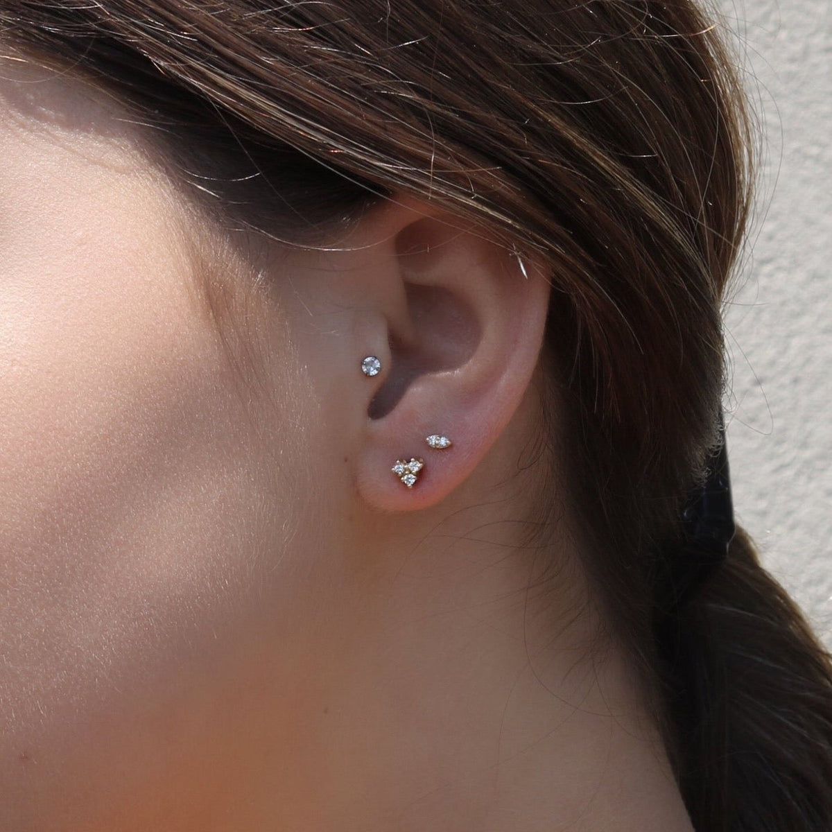 Small Diamond Stud Earrings -14K Yellow Gold Mini Trio Diamonds on models ear- Camille Jewelry